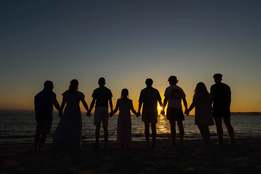 Grupo de pessoas de mãos dadas ao entardecer