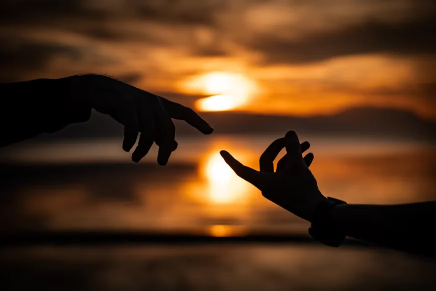 Duas mãos se aproximando ao pôr do sol